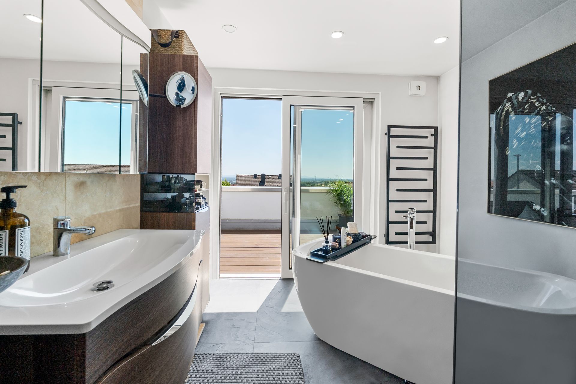 Modernes Badezimmer mit freistehender Badewanne und Zugang zu einer Terrasse.