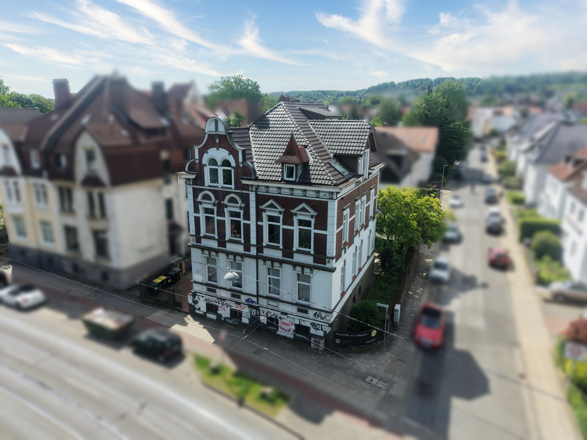 Mehrstöckiges Wohnhaus mit Erker und verziertem Giebel an einer Straßenecke.