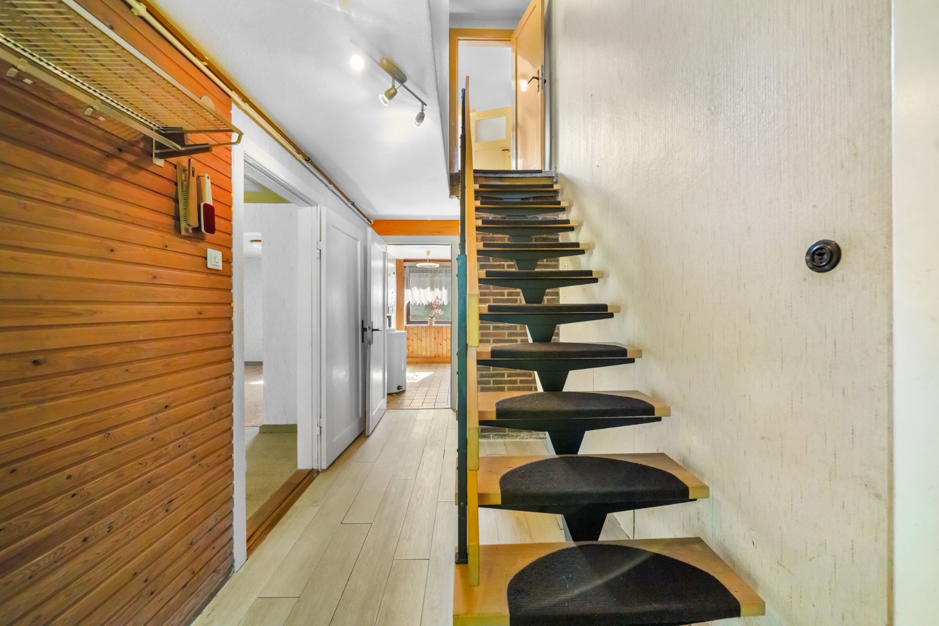 Helle Diele mit Holztreppe und Holzverkleidung an der linken Wand.