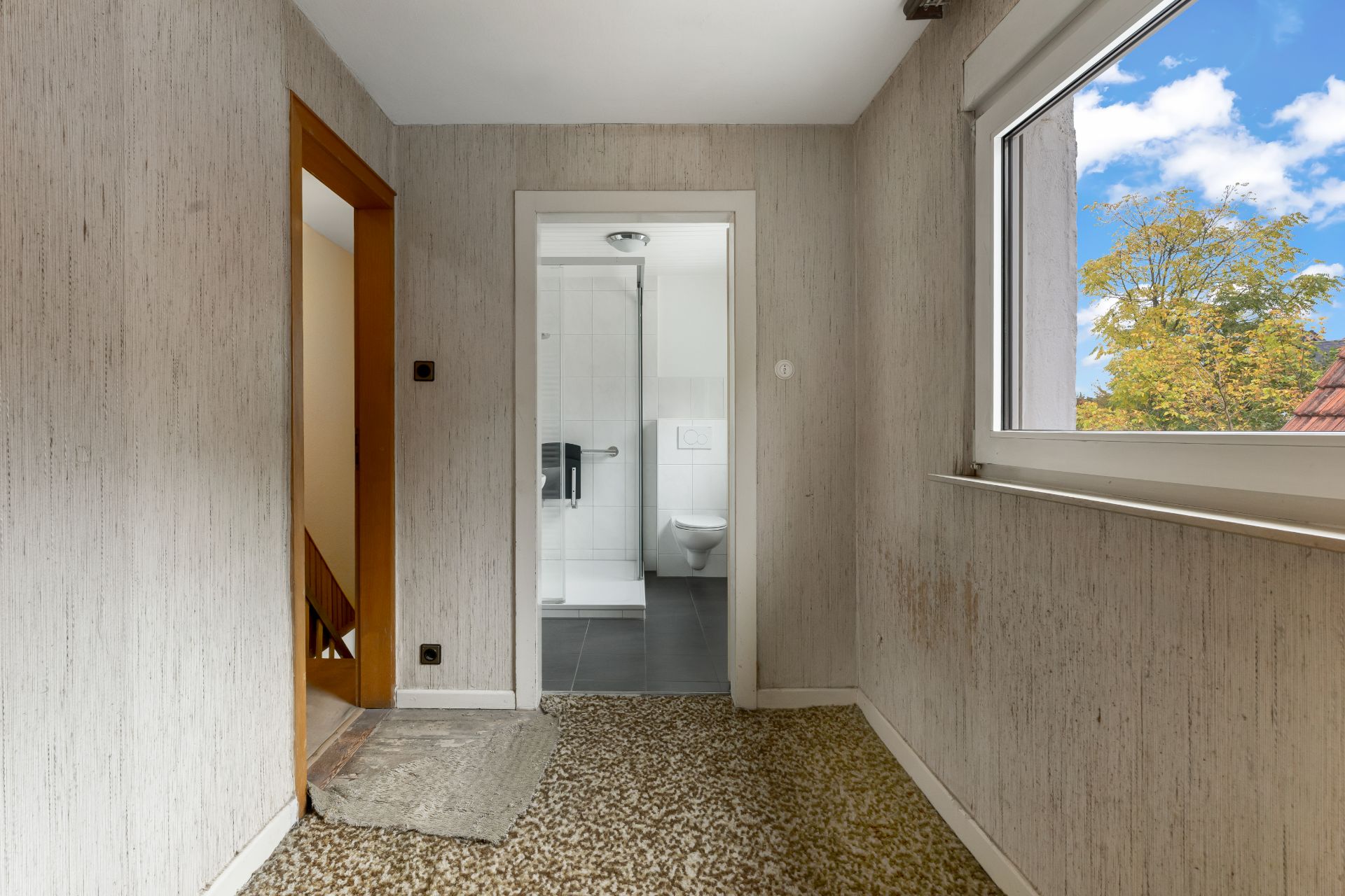 Flur mit Blick auf ein Badezimmer und Fenster mit Sicht auf Bäume.
