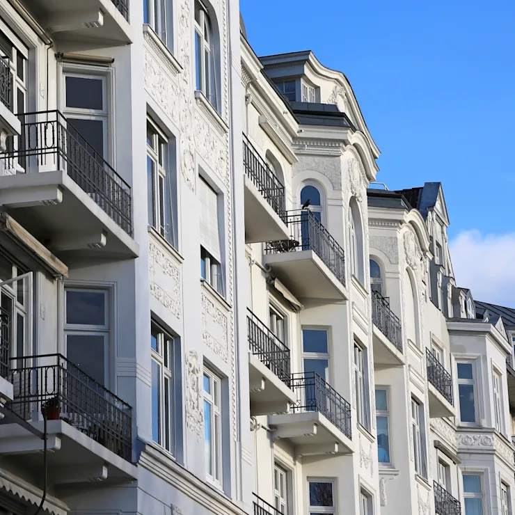 Mehrstöckiges Wohngebäude mit Balkonen und verzierten Fassaden vor blauem Himmel.