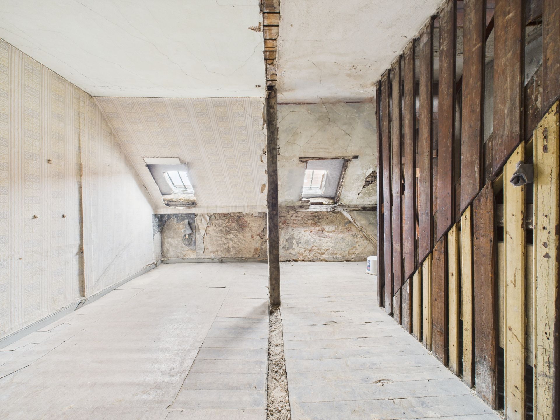 Dachbodenraum mit zwei Dachfenstern und sichtbarer Wand- und Bodensanierung.
