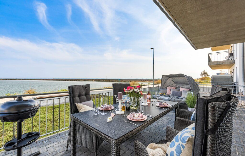 Terrasse mit Sitzgruppe, Gartengrill und Ausblick aufs Wasser.