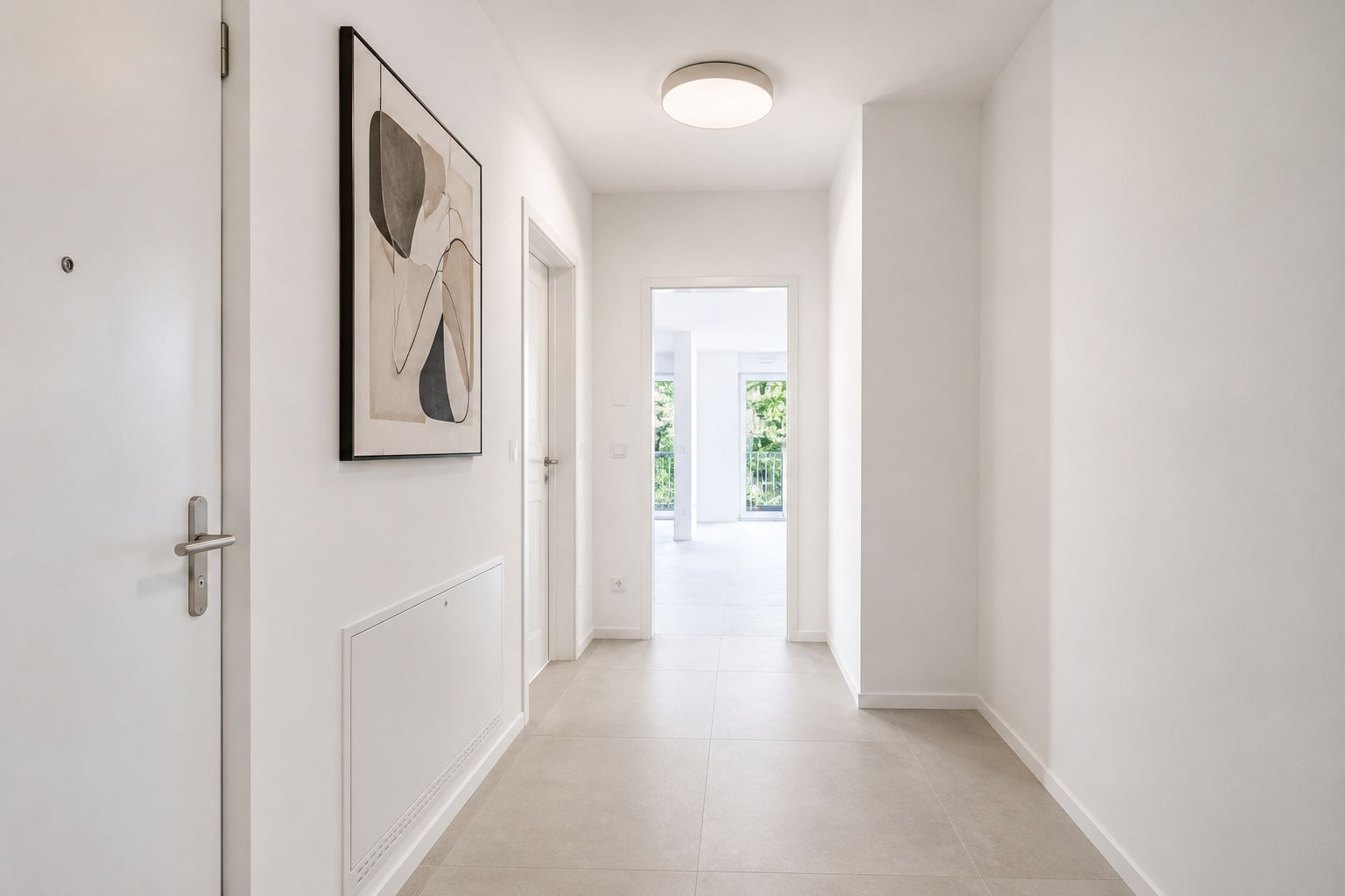 Heller Flur mit weißer Tür, abstraktem Bild an der Wand und Blick in einen Raum mit Fenstern.