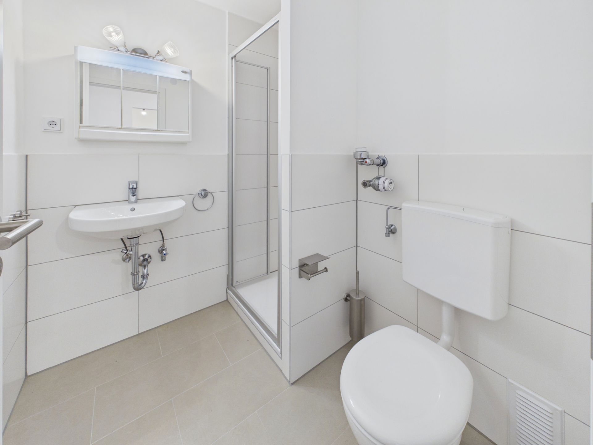 Helles Badezimmer mit WC, Waschbecken, Spiegel und Duschkabine.