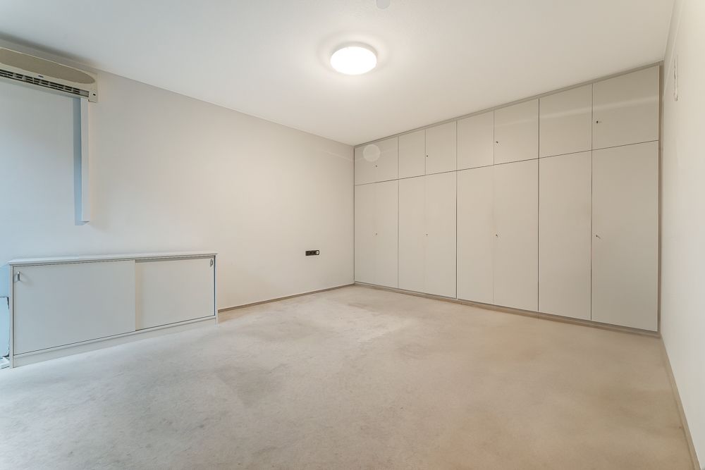 Heller leerer Raum mit großen Einbauschränken an einer Wand und Deckenleuchte.