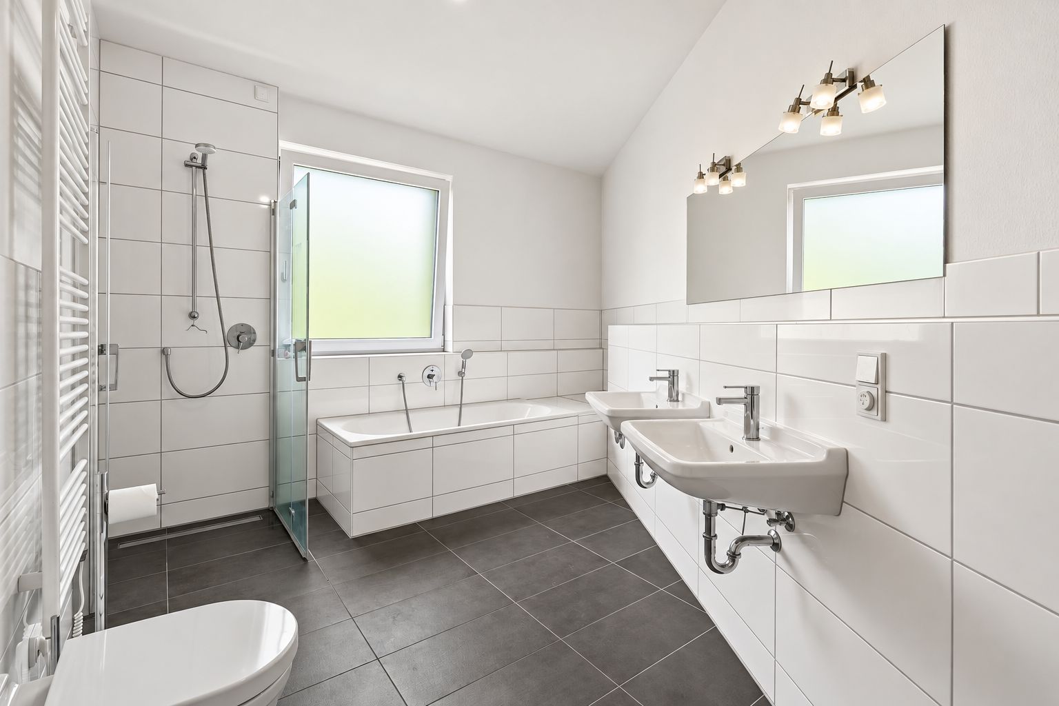 Modernes Badezimmer mit Badewanne, Dusche, zwei Waschbecken und großem Spiegel.