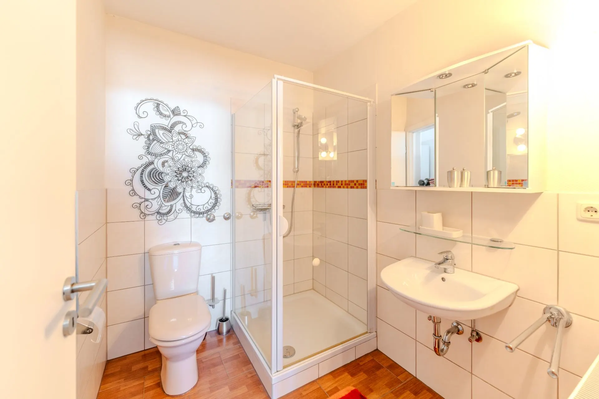 Helles Bad mit Toilette, Dusche, Waschbecken und Wanddekoration mit floralem Muster.