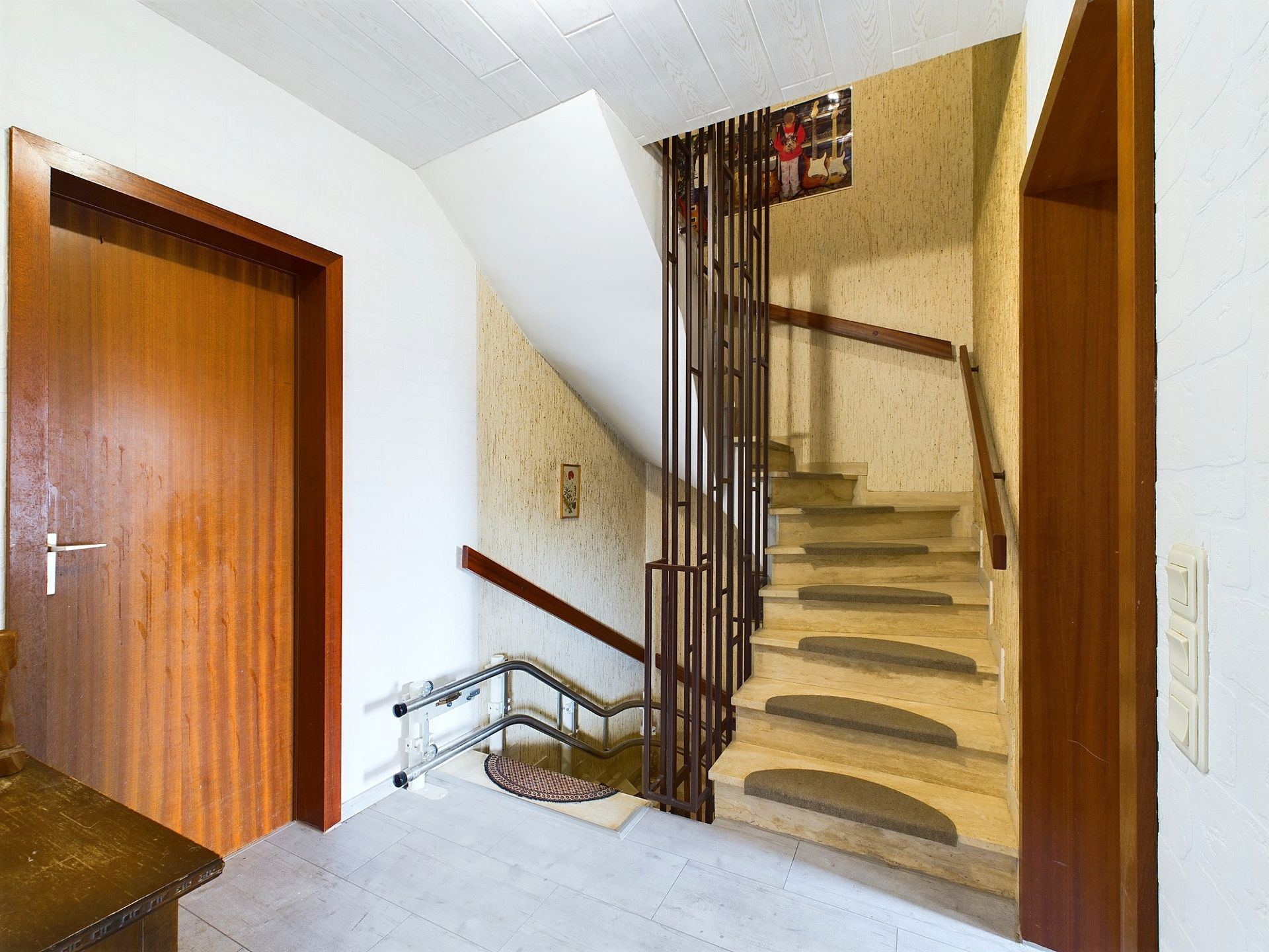 Treppenhaus mit Holzgeländer und zwei Holztüren in einem Wohnhaus.