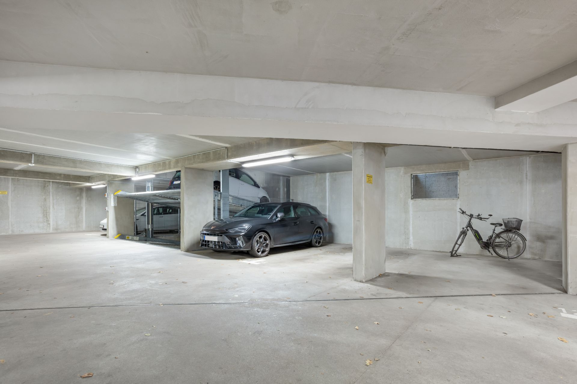 Tiefgaragenstellplatz mit einem Auto und einem Fahrrad vor Betonwänden.
