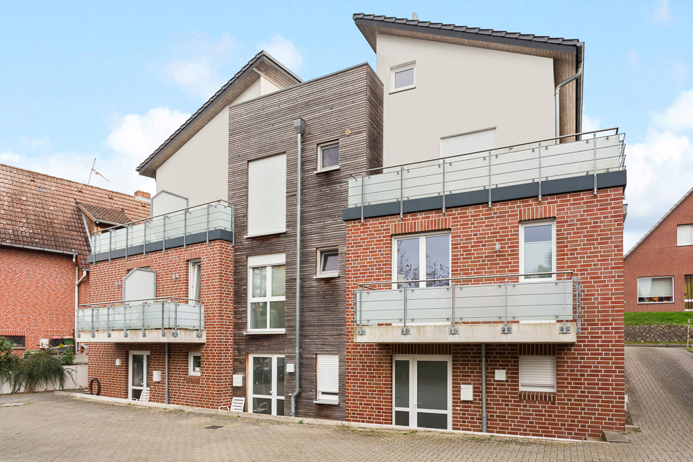 Modernes Wohnhaus mit roten Ziegelwänden, Balkonen und großen Fenstern.