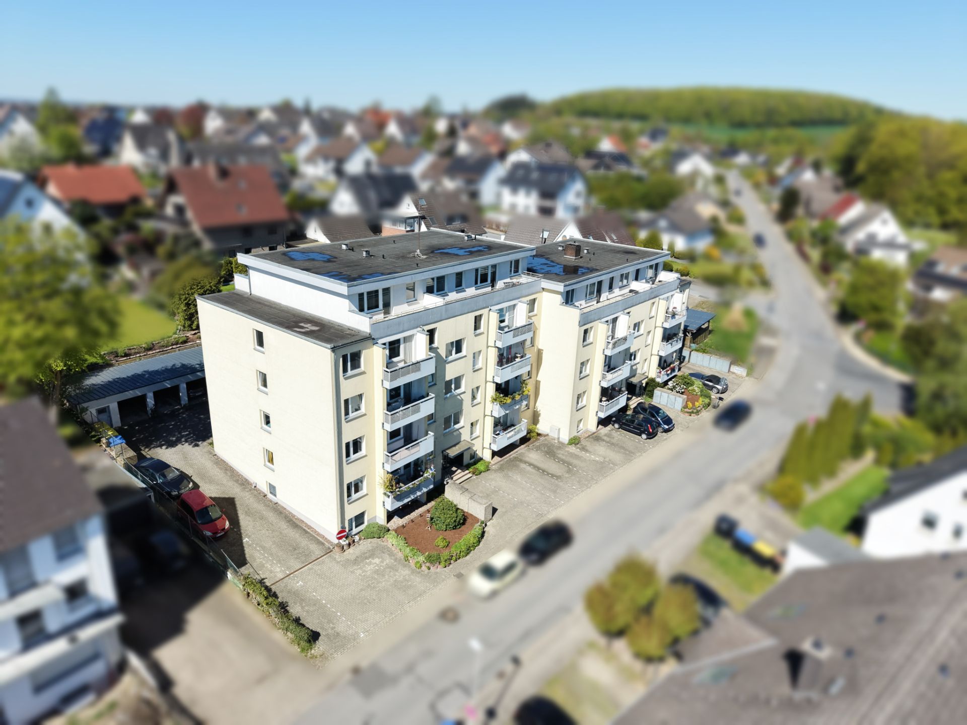 Mehrstöckiges Wohngebäude mit Balkonen und Parkplätzen an einer Straße.