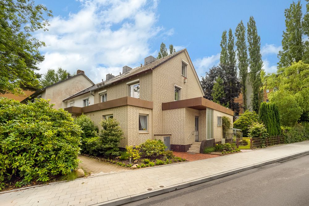Zweistöckiges Wohnhaus mit hellem Mauerwerk, Garten und Gehweg an einer ruhigen Straße.
