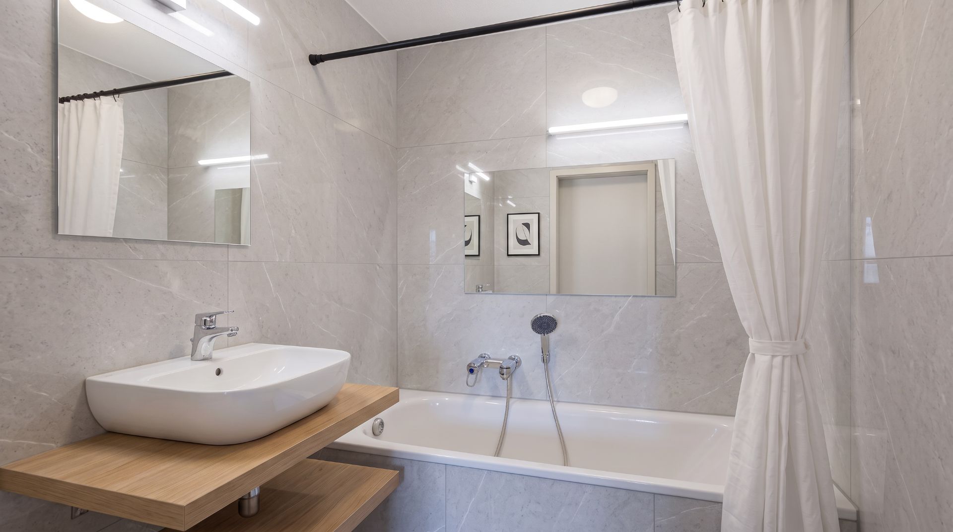 Modernes Badezimmer mit Waschbecken, Badewanne, Spiegel und Duschvorhang.