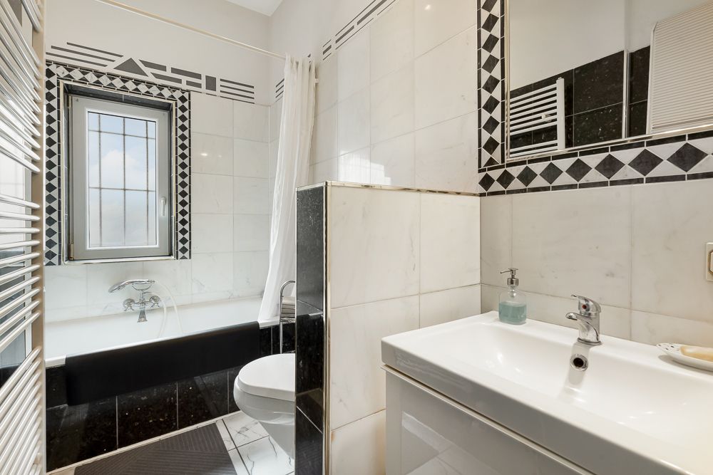 Modernes Bad mit Badewanne, Waschbecken, Spiegel und Fenster.