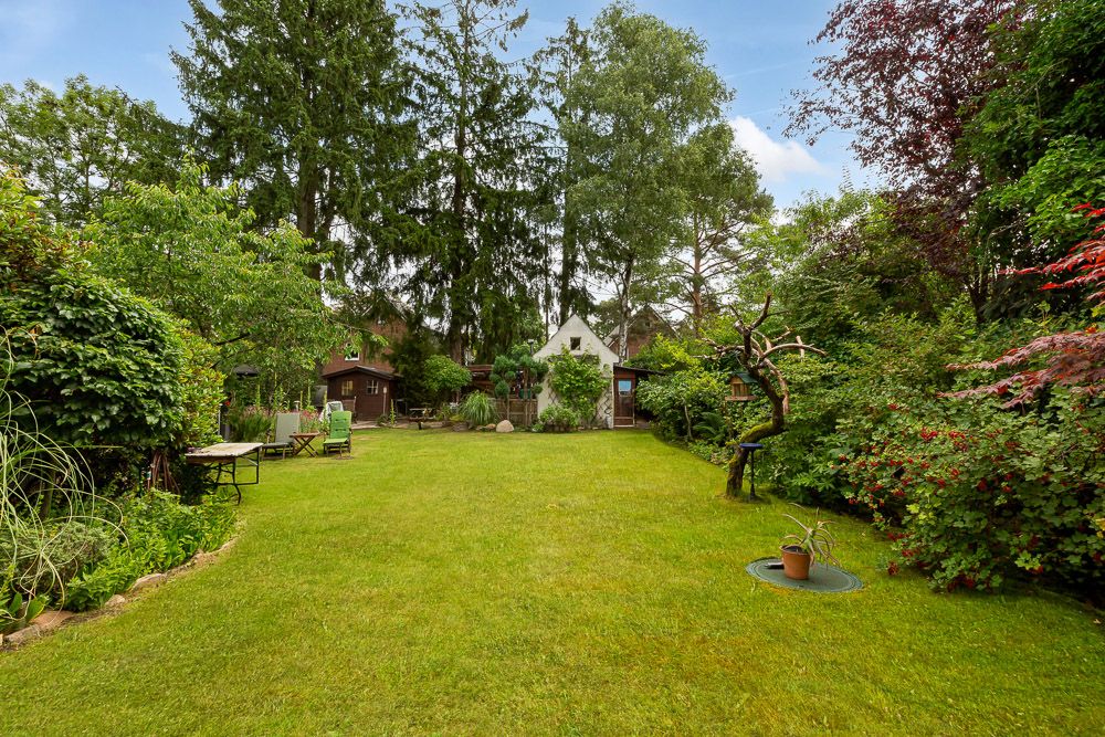 Großer, gepflegter Garten mit Rasenfläche, Bäumen, Sträuchern und Gartenmöbeln.
