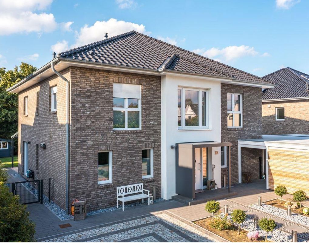 Modernes zweistöckiges Wohnhaus mit Klinkerfassade, Vorgarten und Carport.