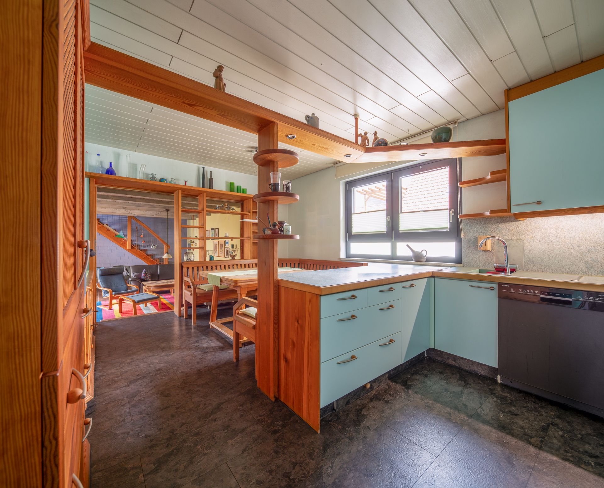 Helle Küche mit blauen Schränken und Holzelementen, angrenzend an ein Esszimmer.