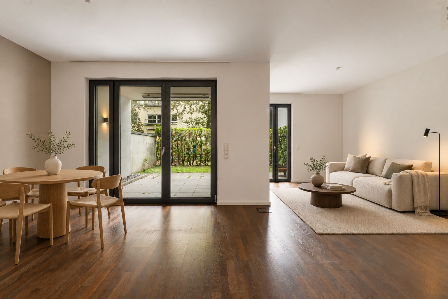 Helles Wohnzimmer mit Holzfußboden, Esstisch, Sofa und Zugang zur Terrasse mit Garten.