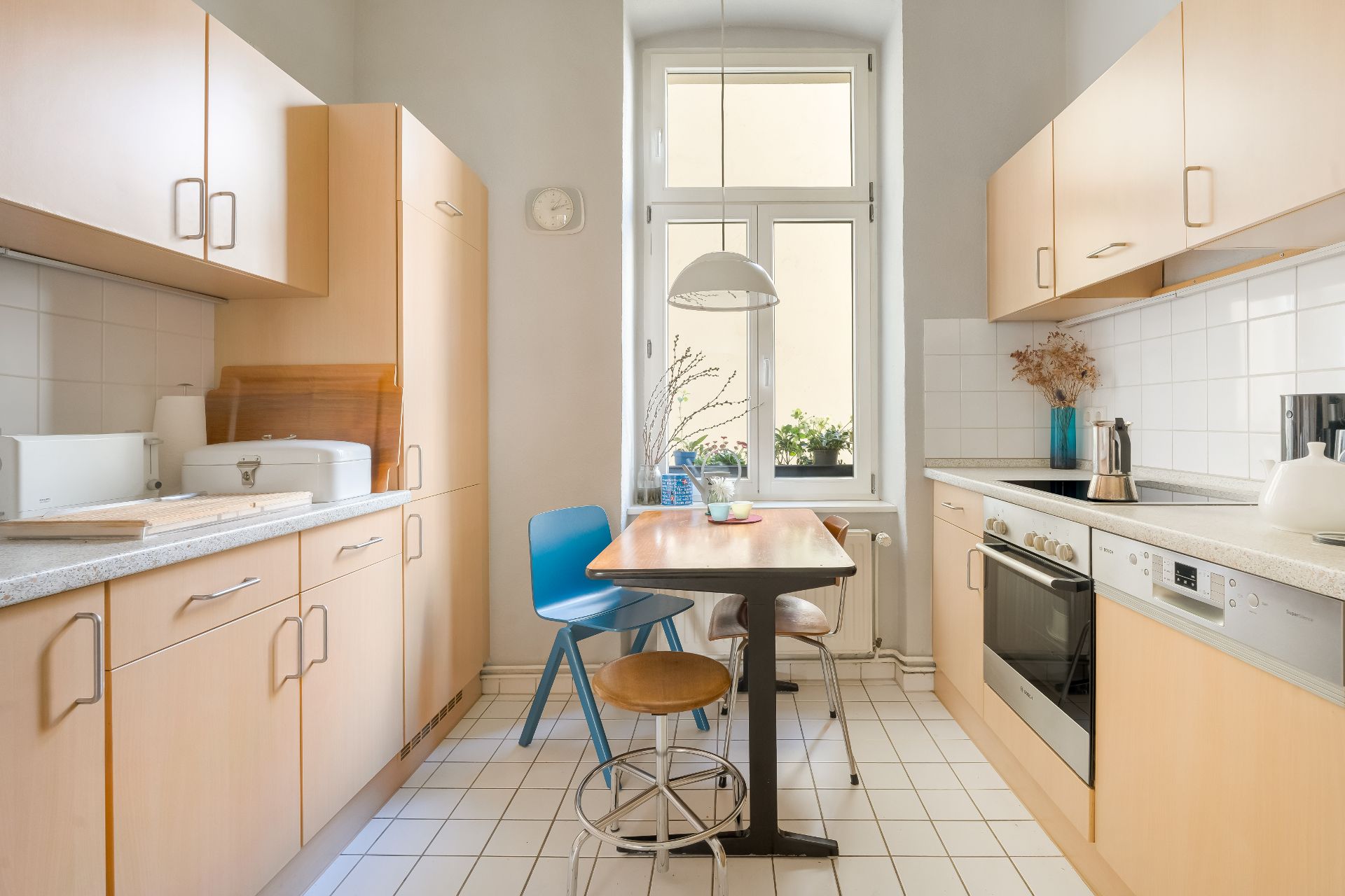 Helle Küche mit Esstisch, zwei Stühlen, Fenster und modernen Holzmöbeln.
