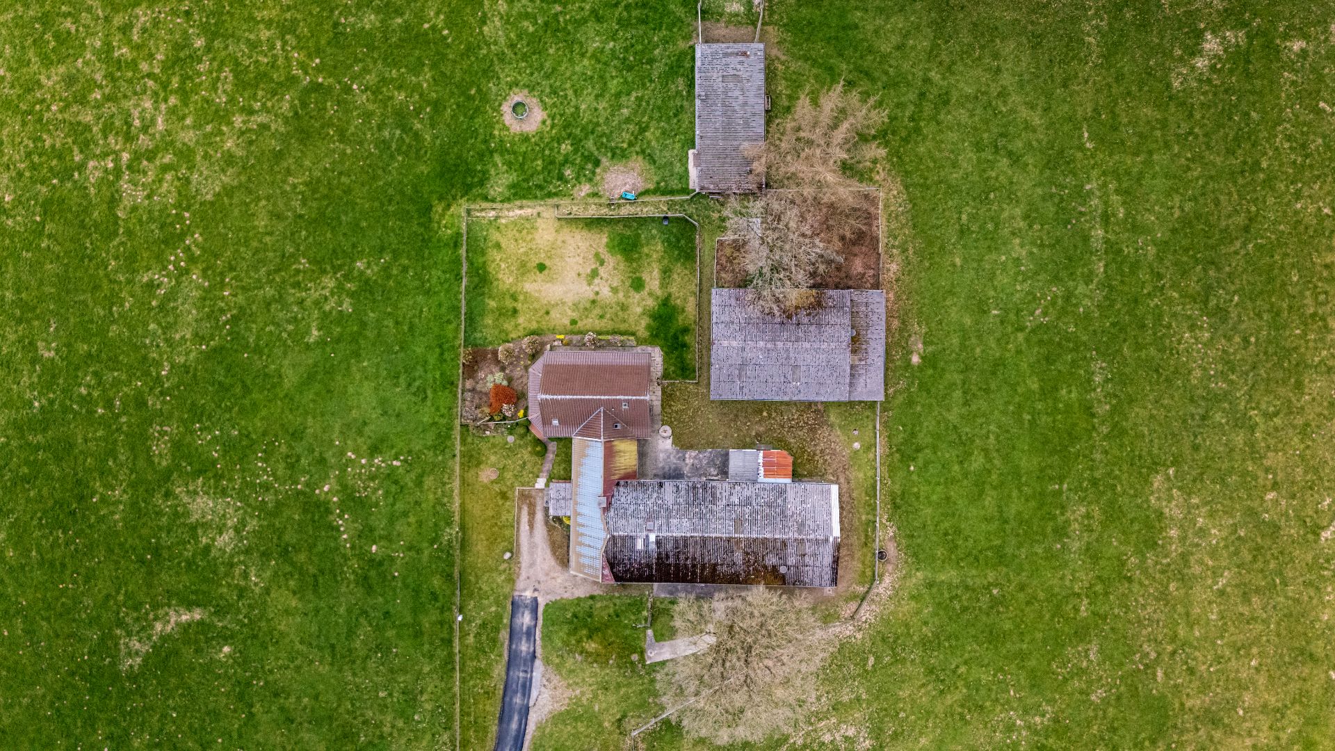 Luftaufnahme eines Hauses mit Nebengebäuden und großem, grünen Garten.