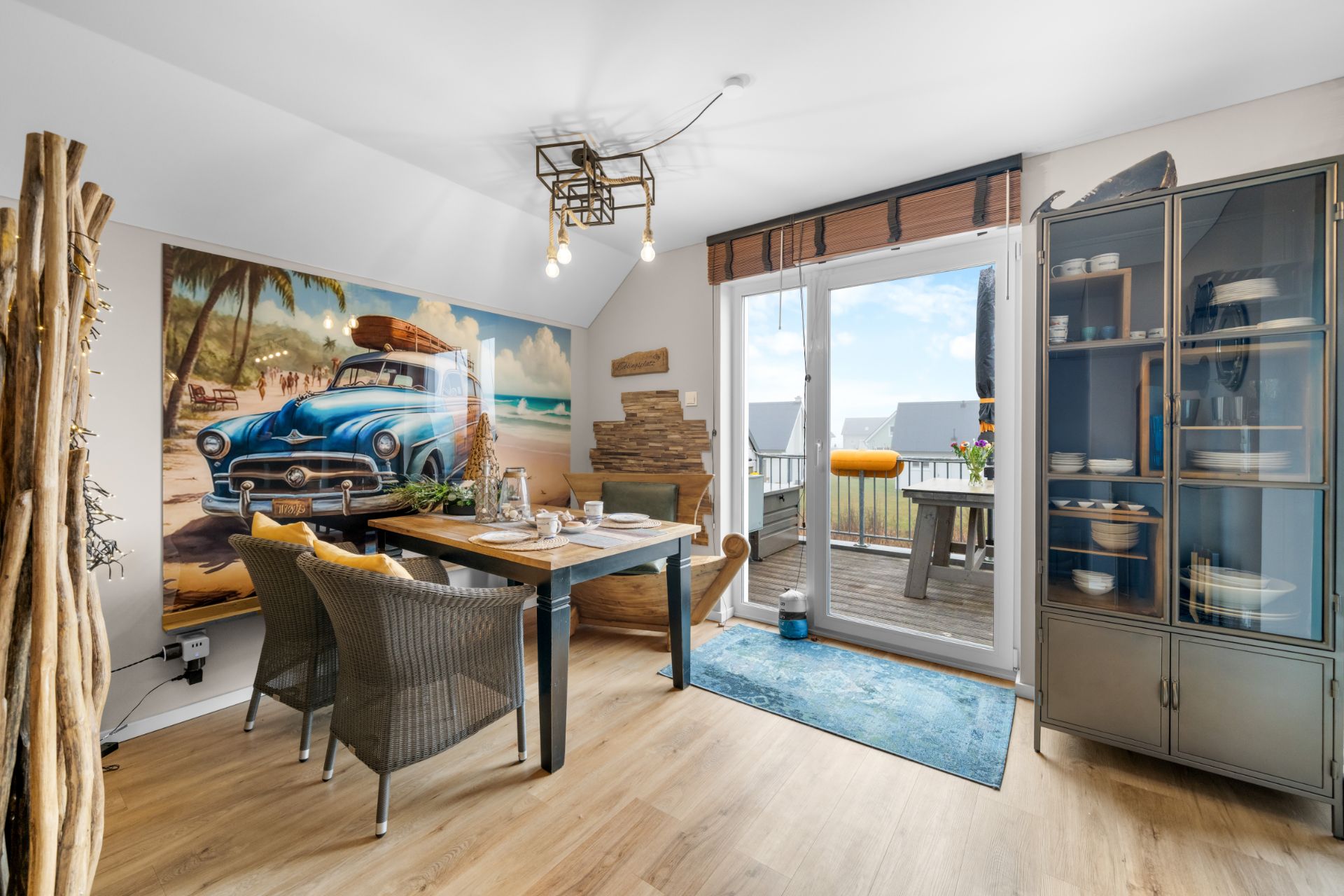 Essbereich mit Holztisch, Stühlen, großem Wandbild und Zugang zu einem Balkon.