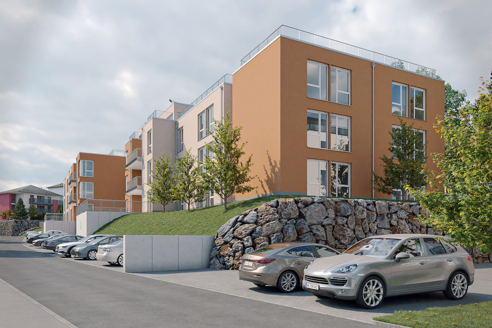 Mehrfamilienhaus mit oranger Fassade, Parkplätzen und Bäumen davor.