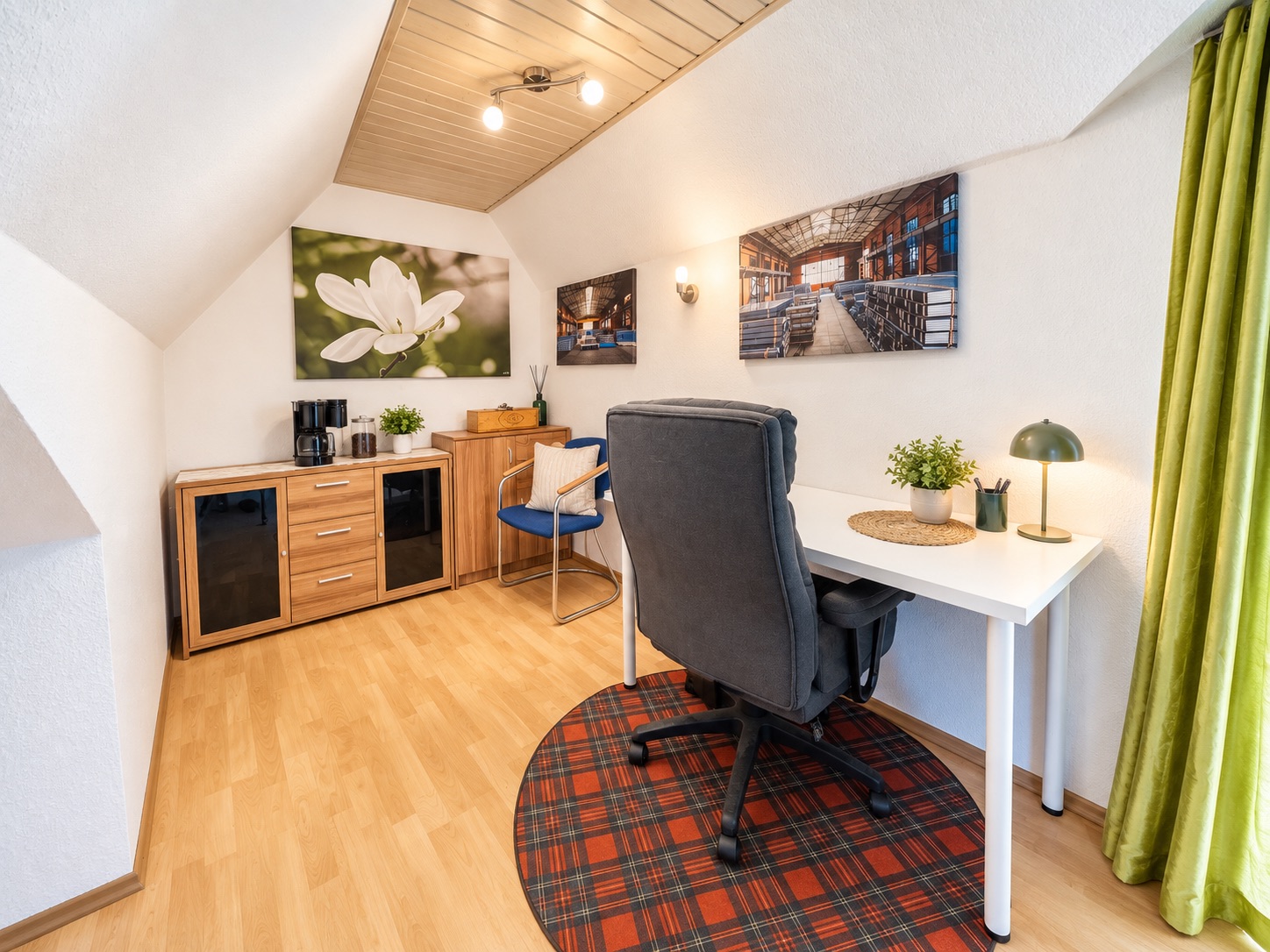 Gemütliches Arbeitszimmer mit Schreibtisch, Stuhl, Kommode und Wandbildern.
