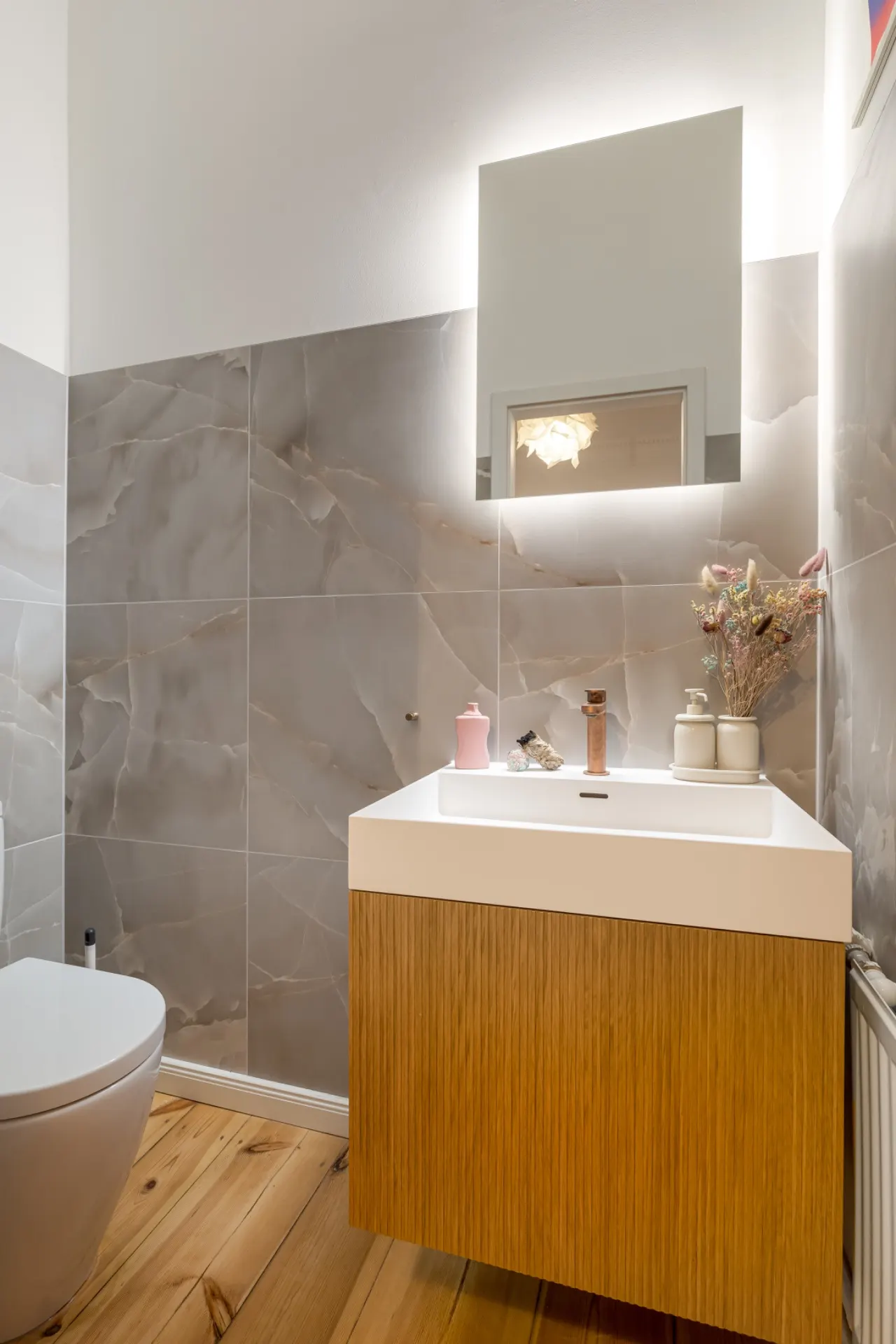 Modernes Badezimmer mit Holzfußboden, Waschbecken, Spiegel und WC.