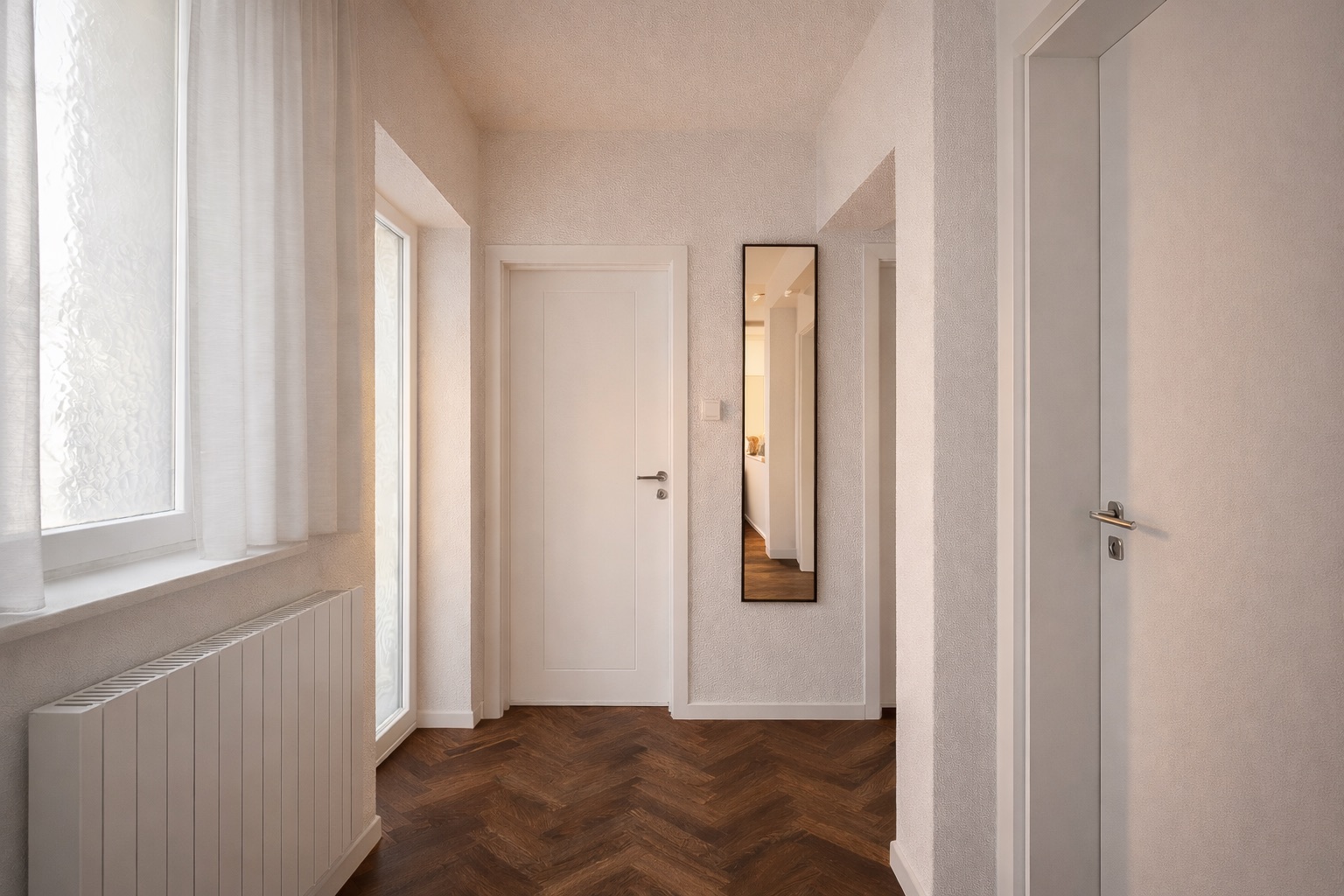 Heller Flur mit Holzboden, weißen Türen, Fenster, Heizkörper und Wandspiegel.