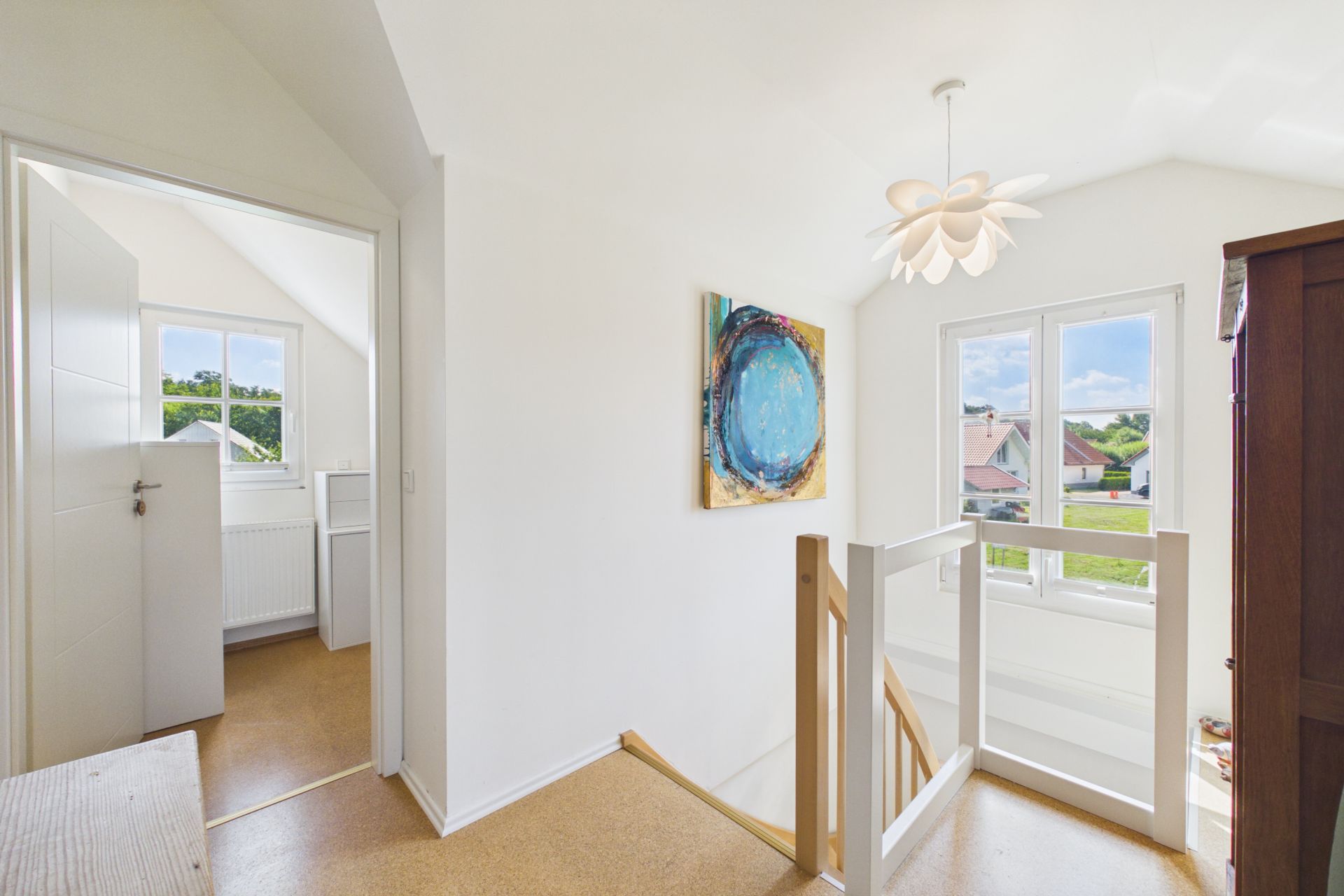 Heller Flur mit Treppe, Fenster, modernem Bild und Hängelampe in einem Wohnhaus.