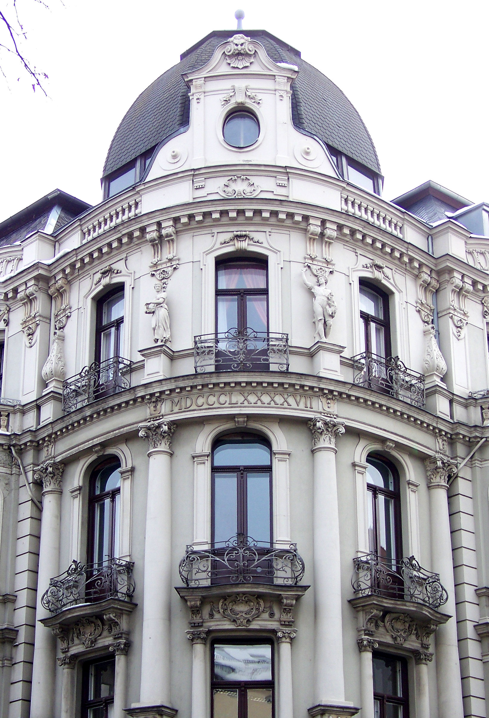Fassade eines historischen Wohngebäudes mit Balkonen, Statuen und Kuppeldach.