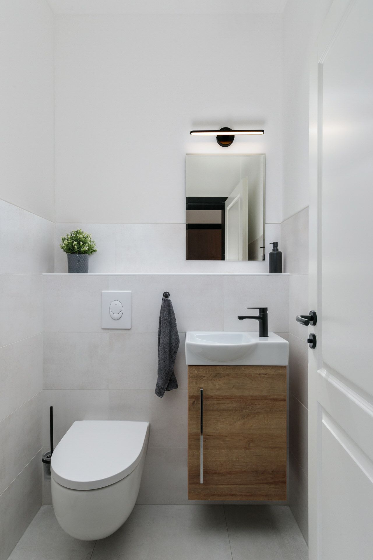 Modernes, kleines Badezimmer mit WC, Waschbecken, Spiegel und Dekopflanze.