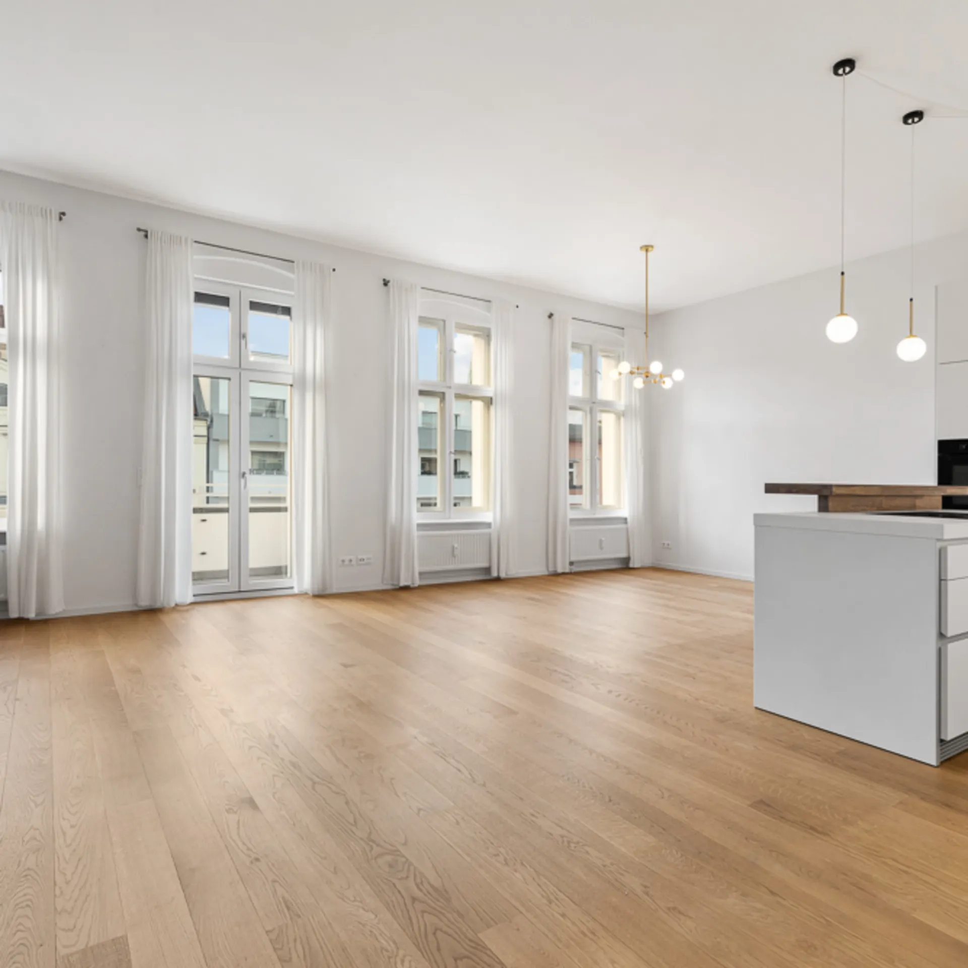 Helles, modernes Wohnzimmer mit offener Küche, großen Fenstern und Holzboden.