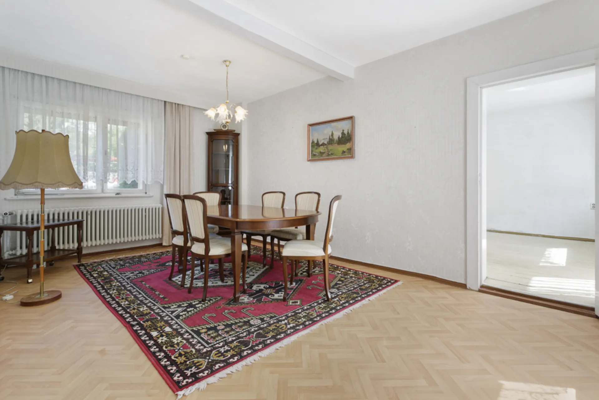 Esszimmer mit Holztisch, sechs Stühlen, Stehlampe und großem Teppich auf Parkettboden.