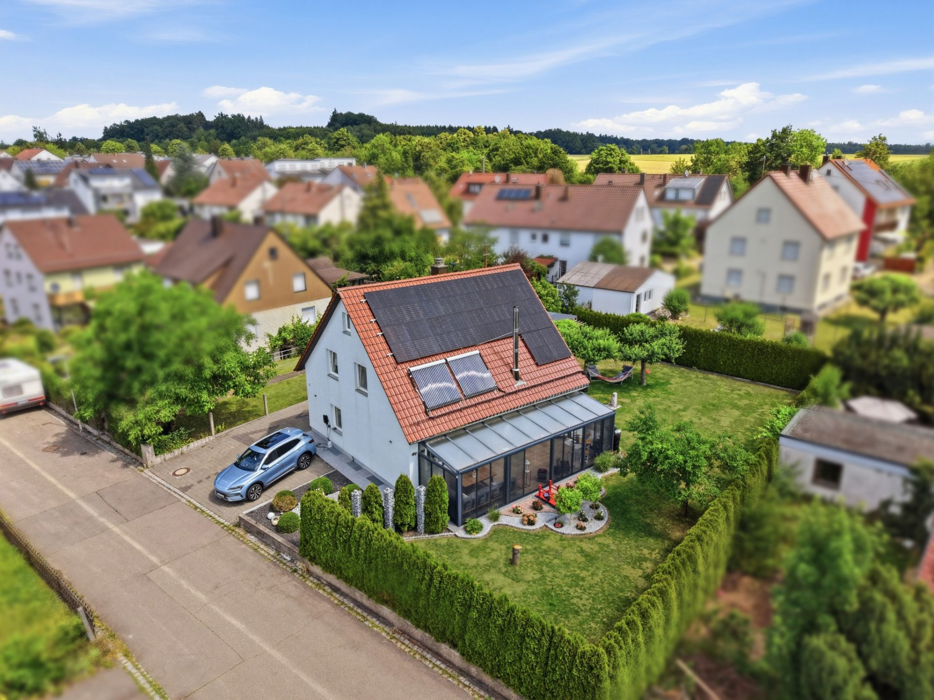 Einfamilienhaus mit Wintergarten, Solarpanels und großem Garten in Wohngegend.