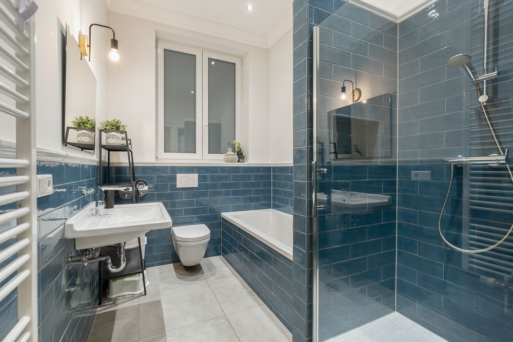 Modernes Bad mit blauen Fliesen, Dusche, Badewanne, WC und Waschbecken.