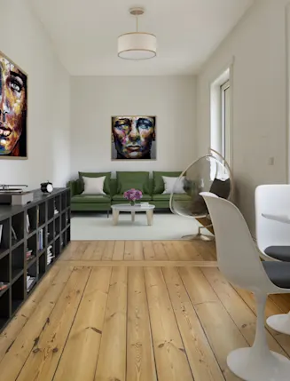 Helles Wohnzimmer mit grünem Sofa, modernen Stühlen, runden Tisch und zwei bunten Porträts an der Wand.