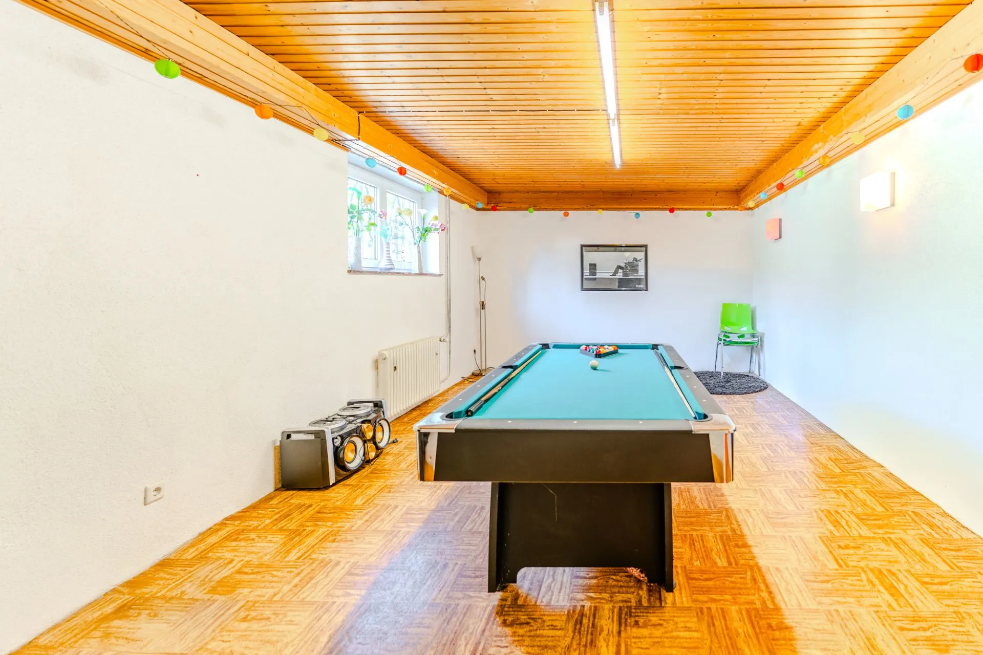Heller Raum mit Billardtisch, Holzdecke, Parkettboden und Stereoanlage.