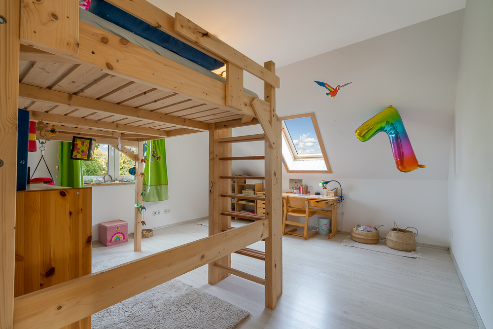 Kinderzimmer mit Hochbett, Schreibtisch, buntem Ballon und Dachfenster.