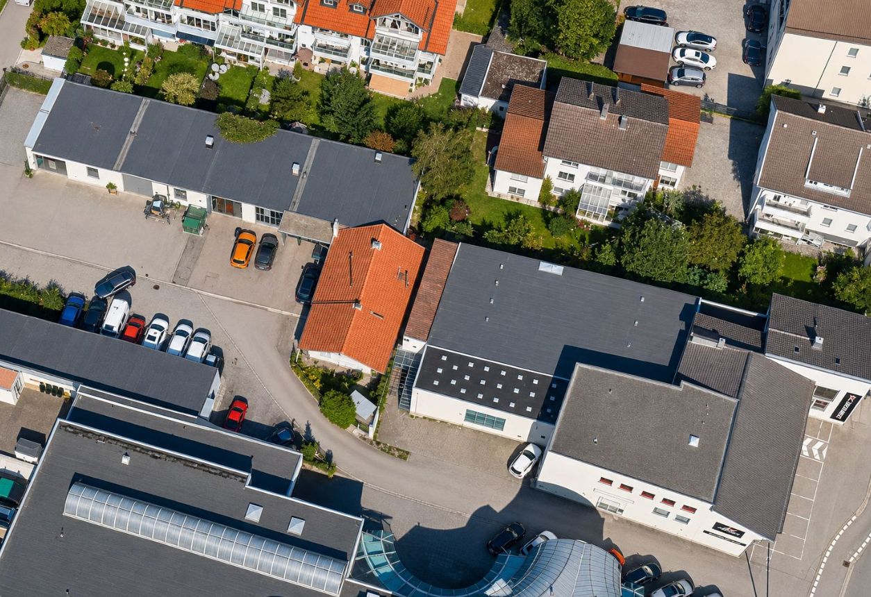 Luftaufnahme von Wohnhäusern mit Gärten und geparkten Autos in einer Siedlung.