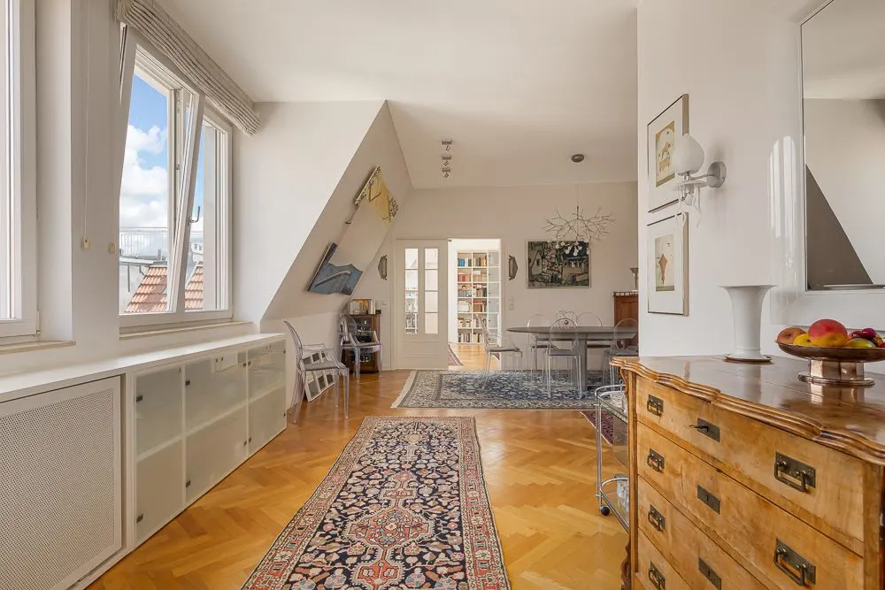 Helles Wohnzimmer mit Parkettboden, Teppichen, Holzmöbeln und großen Fenstern.