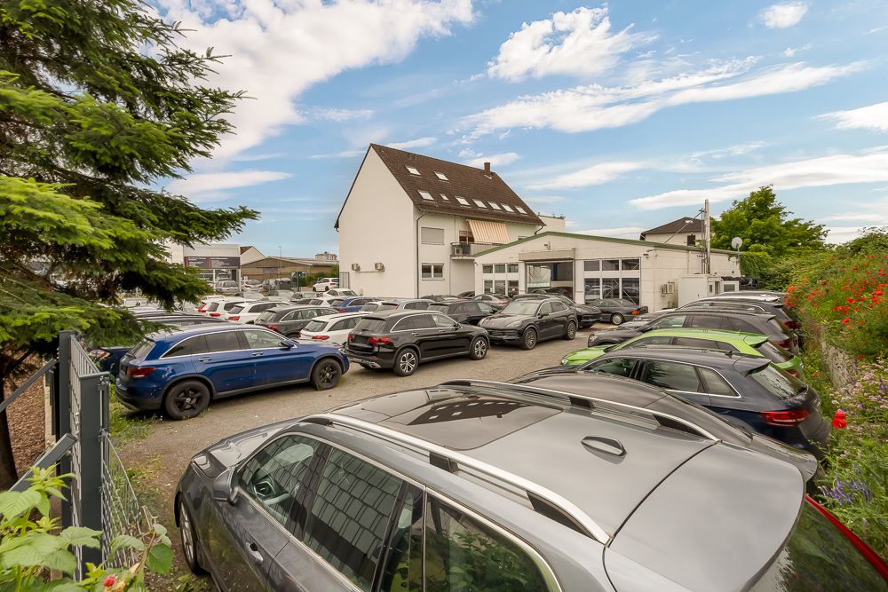 Mehrere geparkte Autos auf einem Hof vor einem Wohngebäude bei Tageslicht.