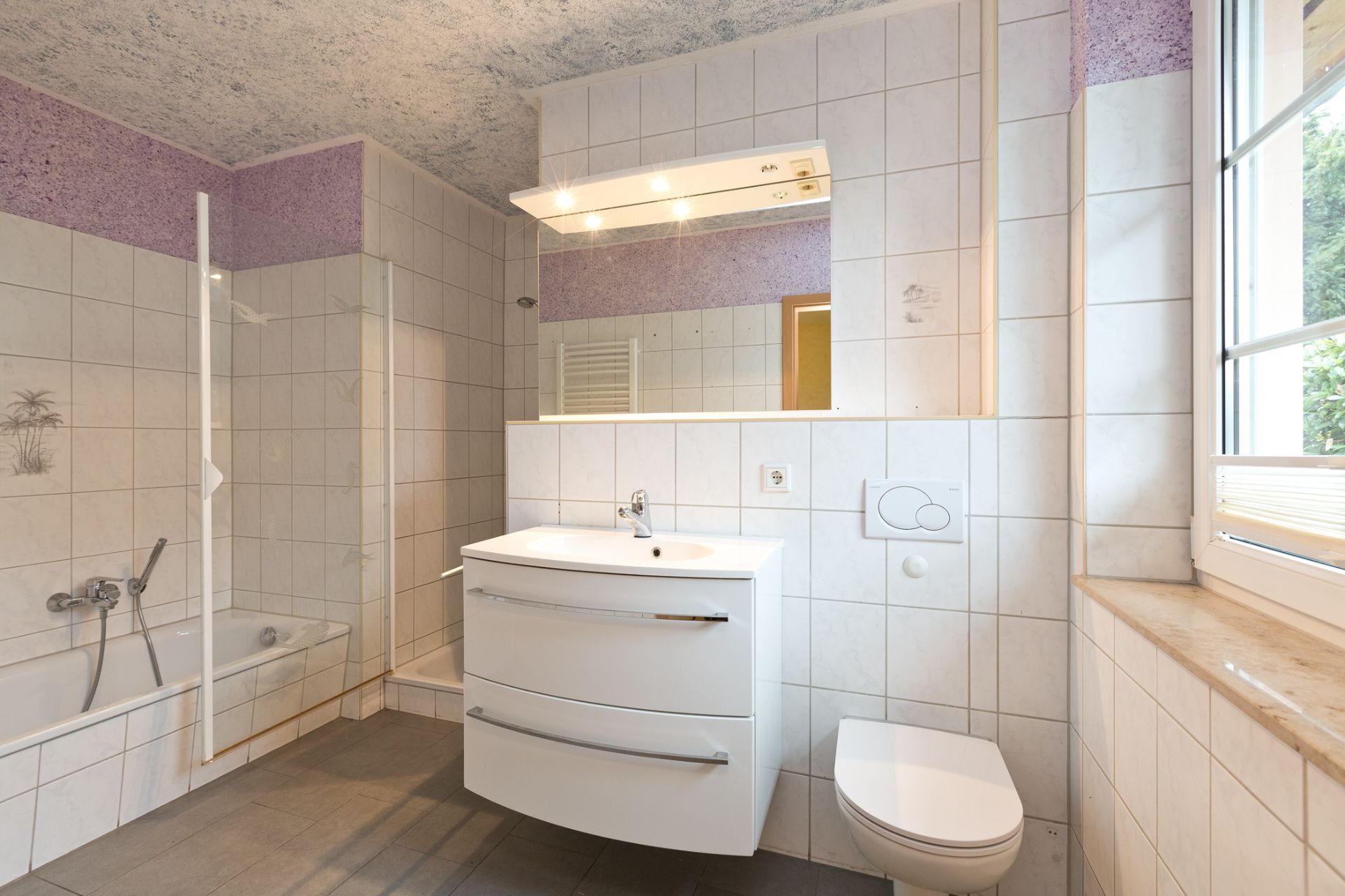 Modernes Badezimmer mit Badewanne, Waschbecken, Spiegel und WC, großes Fenster rechts.