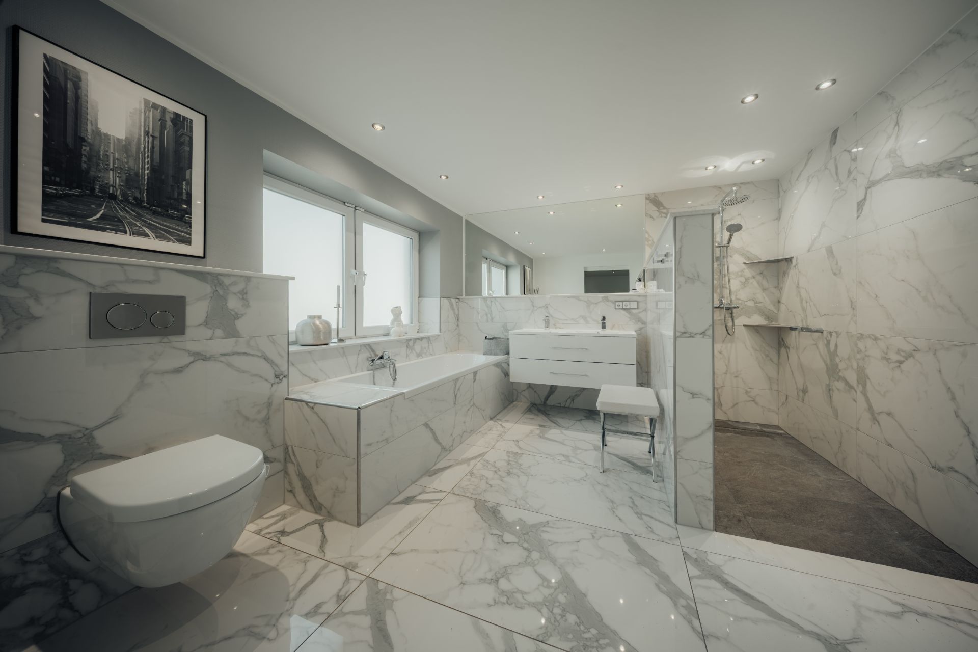 Modernes Badezimmer mit Marmorfliesen, Badewanne, Dusche, WC und großem Spiegel.