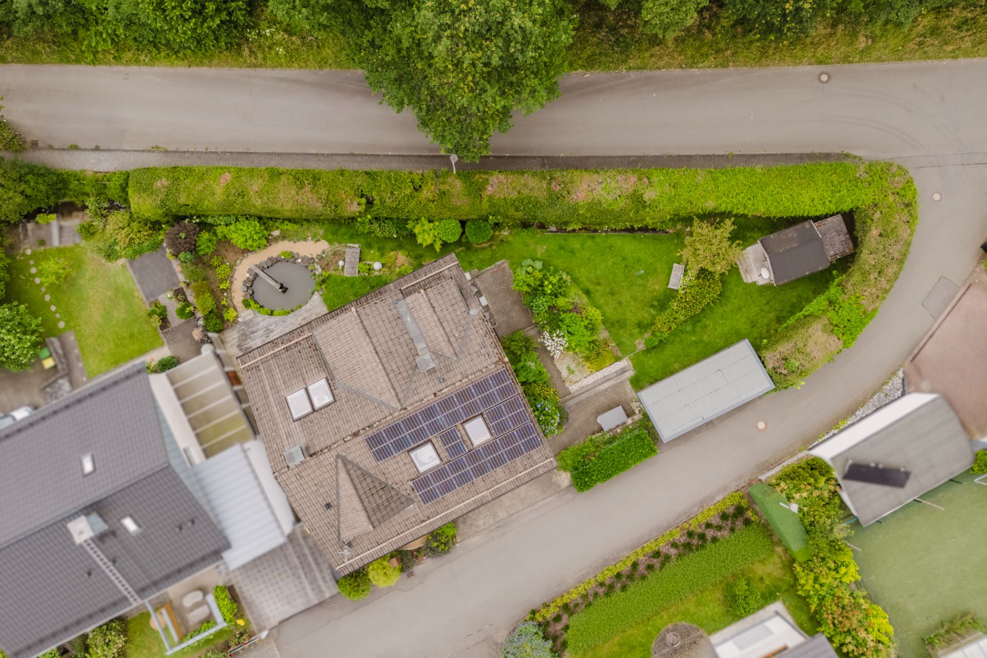 Luftaufnahme eines Wohnhauses mit Solarpanels auf dem Dach und angrenzendem Garten.
