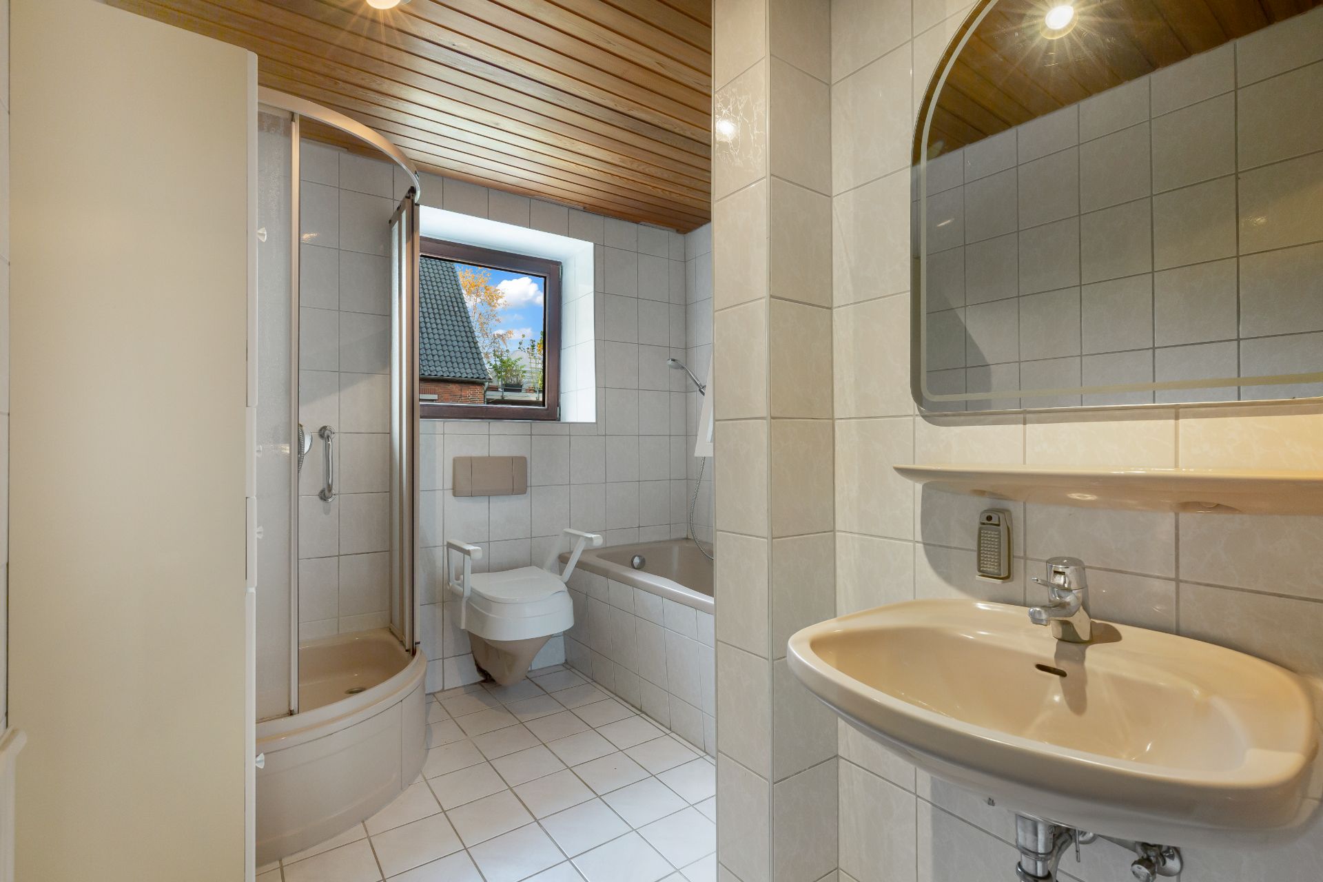 Helles Badezimmer mit Dusche, WC, Waschbecken, Badewanne und Fenster.