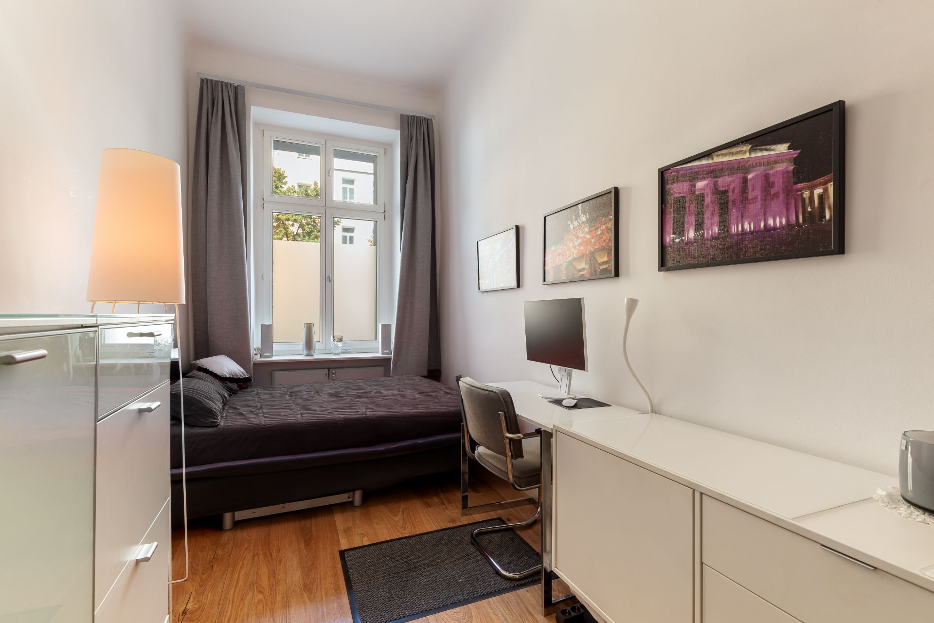 Modernes Schlafzimmer mit Bett, Schreibtisch, Stuhl und großem Fenster mit Vorhängen.