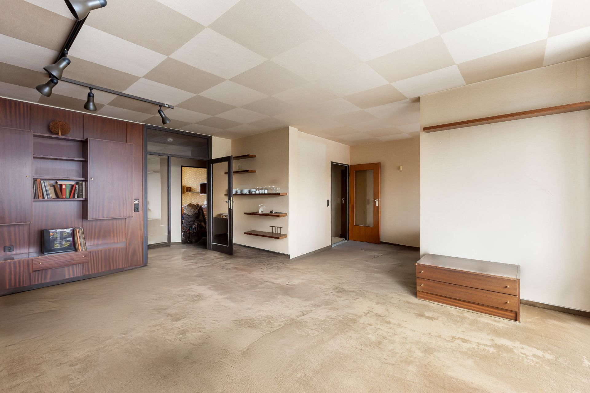 Helles Wohnzimmer mit eingebautem Wandregal, Holzmöbeln und offenen Türen zu anderen Räumen.