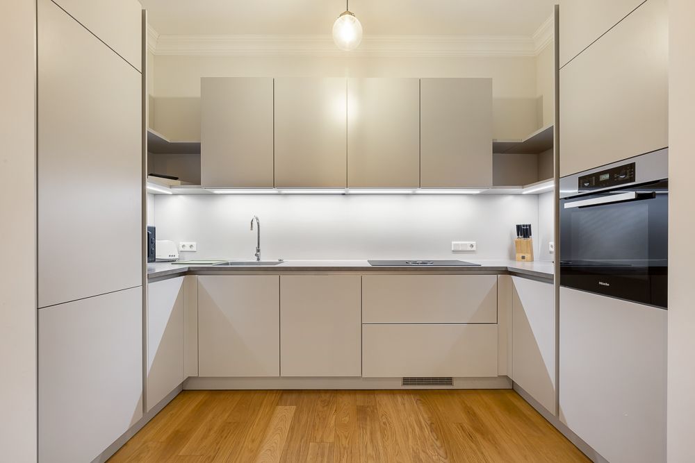 Moderne, helle Einbauküche mit Ober- und Unterschränken sowie Holzfußboden.